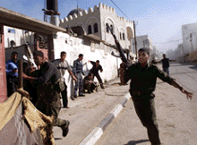Palestinian policemen run for safety as their security headquarters is hit by an Israeli missile in the Gaza Strip on Thursday.