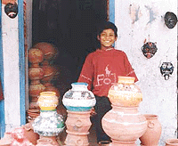 A boy poses with colourfully decorated ‘matkas’ in Ghumar Mandi, Ludhiana.