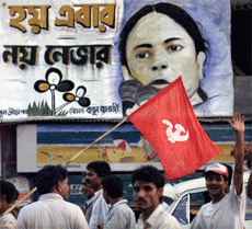 Communist supporters walk past a poster of Mamata Banerjee of the Trinamool Congress party in Calcutta on Sunday. Banerjee's poster has a slogan in the local Bengali language saying, "If not this time, then never (will we win the election)". 