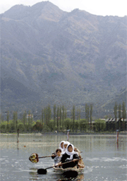 People paddle a boat across Dal lake in Srinagar on Thursday. Compared to the 44 degree Celsius heat blowing across the north Indian plains, the Kashmir valley is a cool, green oasis of open spaces dotted with poplar and chinar trees, of Alpine houses with sloping roofs, ringed by the mountains of the Himalayas.