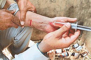 "Injecting death": A drug-addict forces the fatal liquid into his vein, oblivious of the already bleeding arm. Used bottles of Phensedyl and Correx in the backdrop, in Botanical Gardens, Panjab University, Chandigarh, on Saturday, tell us how addicts are throwing their breath to the winds.