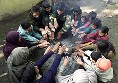 Kashmiri children from border villages warm themselves in a refugee camp