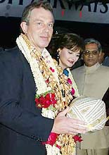 Britain�s Prime Minister Tony Blair is presented with a turban as he and his wife Cherie arrive in Bangalore.