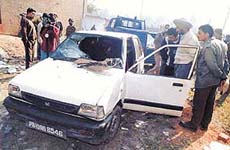 Policemen and relatives of victim examine the charred remains of the car in which an LIC official was found dead, in Ludhiana on Monday. 
