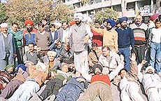 Political activists, traders and employees lie on the road at Dr Sahib Singh Chowk in Sector 17 to protest against paid parking in Chandigarh on Tuesday. 