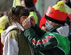 A young Iranian boy helps a girl put on a surgical mask during a youth demonstration against pollution in Tehran on Saturday.
