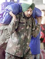 A soldier carries his luggage at a railway station