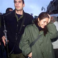 An Israeli policemen leads a woman