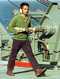 A flight attendant carries two missiles on the deck