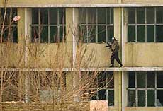 An Afghan fighter is seen moving on to the ledge of the second storey of Mir Wais Hospital in Kandahar on Monday
