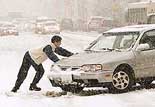 A man tries to get his car up a hill during a heavy snowfall 
