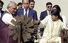 A  girl watches as Prime Minister Atal Behari Vajpayee spins a charkha