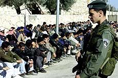 An Israeli soldier watches arrested Palestinian workers