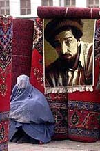 An Afghan woman in a Burqa waits for customers as she sells carpets