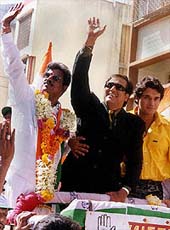Bollywood star Govinda (C) waves while campaigning for Congress candidate
