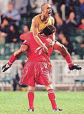 Hong Kong's Aderbal Pericles Farias Filho (top) celebrates with team-mate Gary McKeown after Filho scored a goal during their match against China at the Carlsberg Cup Lunar New Year Tournament on Tuesday. 