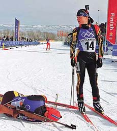 German Kati Wilhelm (L) lies exhausted as compatriot Andrea Henkel stands at the finish line