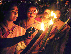 Indian women light torches during a rally