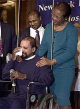 Donovan Cowan (centre) is comforted by his brother Michael and mother Jasmin during a news conference