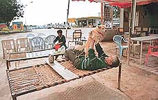 A dhaba worker plays with his pet as there is no customer due to the closure of the Zirakpur-Dera Bassi stretch of the busy Chandigarh-Ambala highway for repair of the Ghaggar bridge near Bhankharpur.
