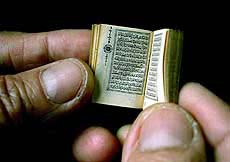 A man holds a tiny edition of the Koran