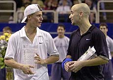 Lleyton Hewitt of Australia and Andre Agassi talk at center court