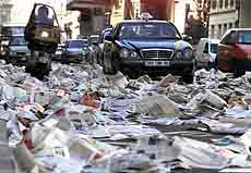 Cars and motorbikes make their way through thousands copies of the free daily