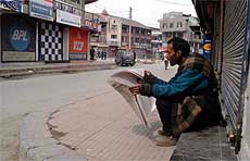 A Kashmiri going through a newspaper in front of a closed shop in the heart of Srinagar as the Kashmir valley observed a general strike 