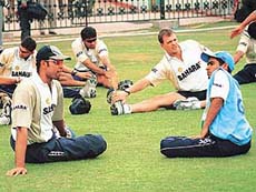 Members of the Indian cricket team stretch under the guidance of team physio