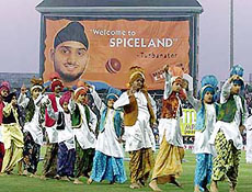 Punjabi folk dancers dance in front of a billboard showing Indian bowler Harbhajan Singh during a break in the second one-day game between India and Zimbabwe in Mohali.