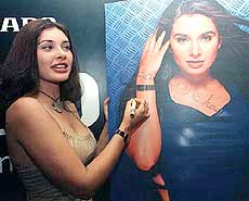 Indian model and actress Lisa Ray signs a poster during a wristwatch promotion in Mumbai on Monday.