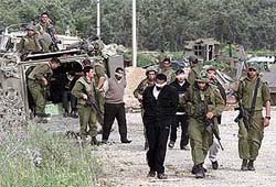 Israeli soldiers guard Palestinians they arrested as they enter the West Bank city of Qalqilya 