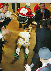 Galatasaray's Asik Emre (L) points at a teammate lying injured in the players' tunnel following clashes with Italian carabinieri 