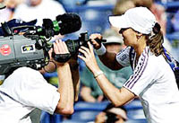 Martina Hingis of Switzerland autographs a television camera lens