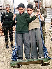 A soldier pushes Kashmiri orphans on a newly donated swing