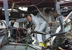 Israeli policemen search the wreckage of a bus which was destroyed by an explosion on the road near the Israeli Arab town of Umm al-Fahm on Wednesday. 