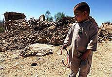 An Afghan boy stands amongst earthquake rubble