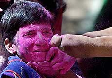 A congenital anomaly patient uses her deformed hand to throw gulal