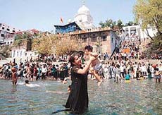 A mother gives her child a "dip" in the Yamuna near the historic Gurdwara Paonta Sahib on the occasion of Hola Mohalla on Friday.