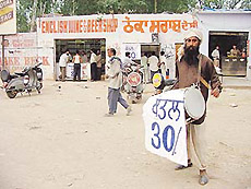 A person beats drum at the Dhakauli barrier on the Ambala-Kalka highway to catch the attention of road users and general public as liquor contractors sold their remaining stocks at rock bottom prices on Sunday.