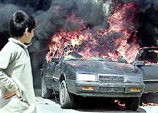 A Palestinian boy watches as smoke billows from a US-made car