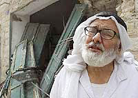 An elderly Palestinian man cries in front of his damaged shop
