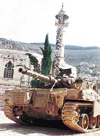An Israeli army tank takes position in front of a mosque