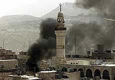 Smoke rises from a house behind a mosque in the Old City in Bethlehem