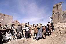 Afghan men, workers from the Kabul municipality, try to pull down the remains of a building with ropes on Thursday