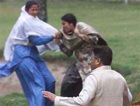 A Pakistani policewoman in blue uniform beats and drags a woman