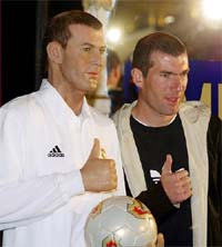 Real Madrid's French International star Zinedine Zidane strikes a pose as he stands next to his wax statue
