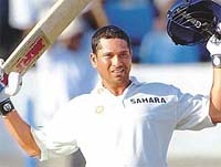 Sachin Tendulkar raises his bat after scoring a century