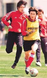 Chinese national soccer team's Li Weifeng (front) drives the ball past Qu Bo (rear) during a training session in Kunming, Yunnan province