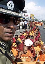 A Sri Lankan police officer stops Buddhist monks participating in a protest 